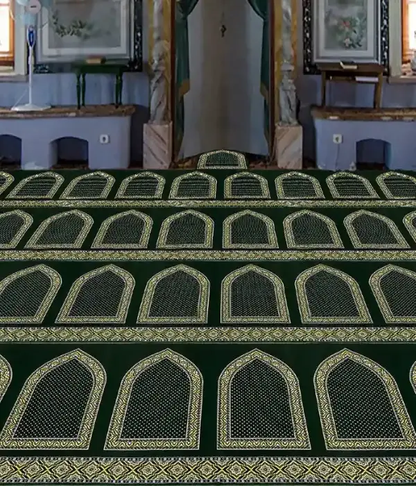 Green prayer carpet (musalla) with multiple rows of golden arch patterns in a mosque interior.